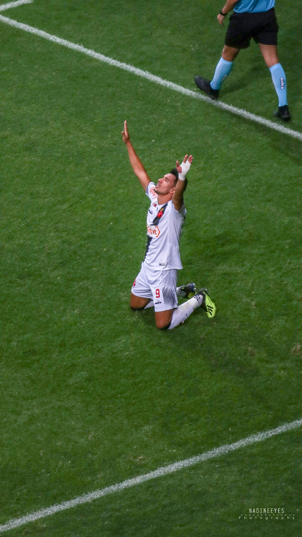 Ein Fußballspieler kniet auf dem Boden und streckt die Arme aus, um zu feiern, trägt eine Sportuniform und Fußballschuhe.