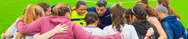 Eine Gruppe von Frauenfußballspielerinnen umarmt sich auf einem Feld.