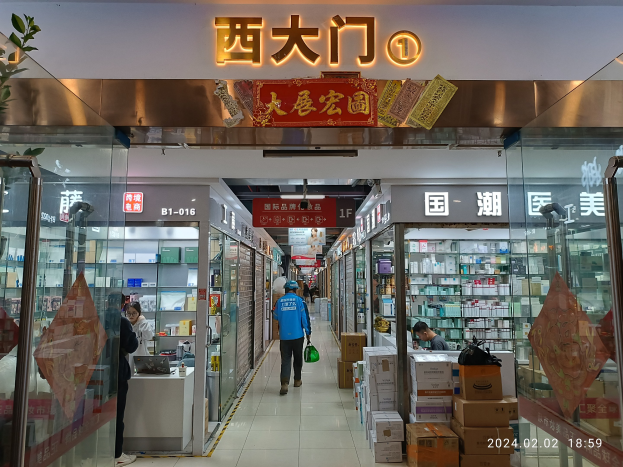 Innenseite einer chinesischen Apotheke mit Glaswänden, einer Pflanze links, Regalen mit Artikeln, verstreuten Kartons und einem Namensschild oben, das auf eine chinesische Drogerie hinweist.