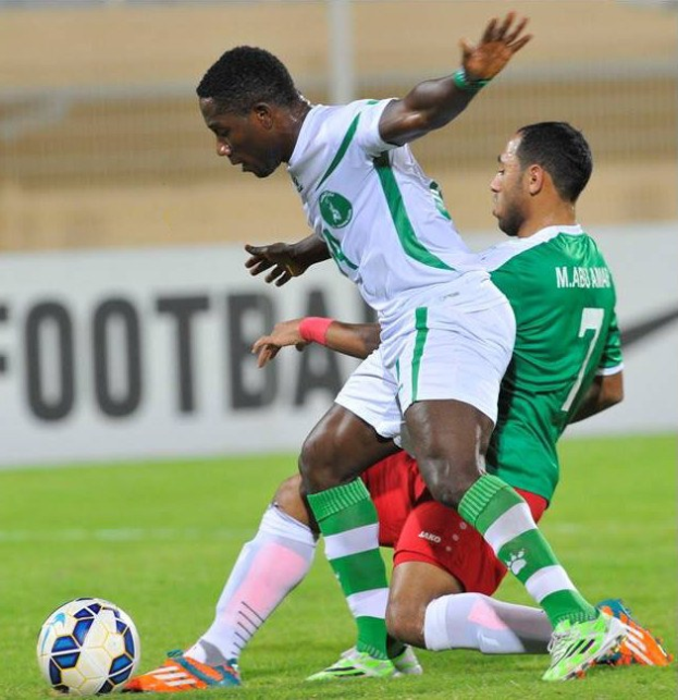 Zwei Männer spielen Fußball auf einem Rasenfeld mit einem unscharfen Hintergrund, der den Text "Nigeria vs Senegal - Africa Cup of Nations" zeigt.