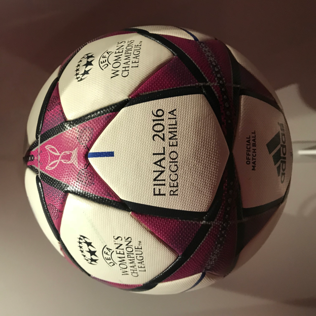 Ein Fußball auf einem weißen Tisch mit der Aufschrift "UEFA Frauen Champions League Finale 2016" in Weiß, Rosa und Schwarz.