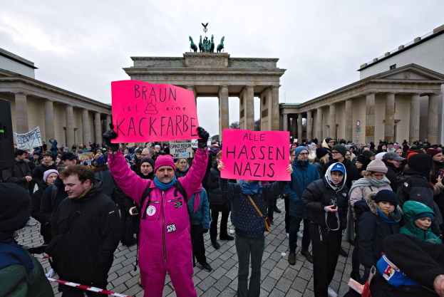 Gruppe von Menschen protestiert vor dem Reichstagsgebäude in Berlin und hält Schilder gegen die Anti-Nazis-Bewegung der deutschen Regierung.