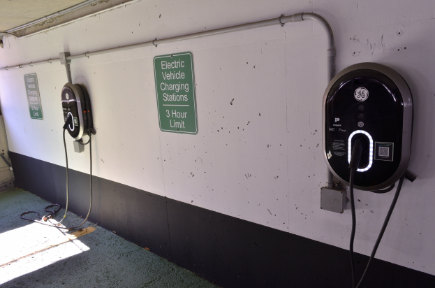 Elektrofahrzeug-Ladestationen an einer Wand in einer Tiefgarage montiert, mit Informationsschildern darüber und dem Boden darunter sichtbar.