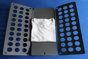 Weißes T-Shirt auf einer blauen Oberfläche neben einem schwarzen und aschgrauen Kleiderordner mit mehreren Löchern.