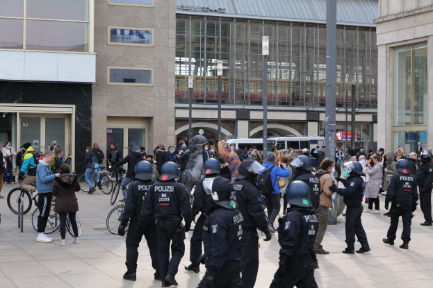 Eine Gruppe von Polizisten in Helmen, die vor einer Menge mit Fahrrädern stehen, mit Glasgebäuden, Laternen und Fahrzeugen im Hintergrund.