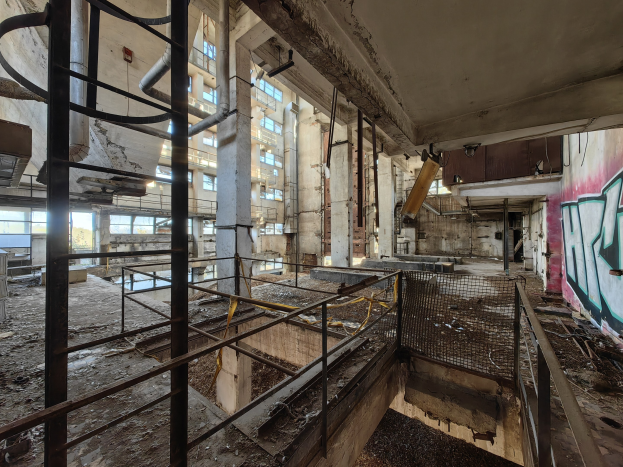 Verlassene Gebäudeinnenseite mit Graffiti an den Wänden, Geländern, Pfählen, Rohren und zerbrochenen Fenstern, die Zeichen von Vernachlässigung zeigen.