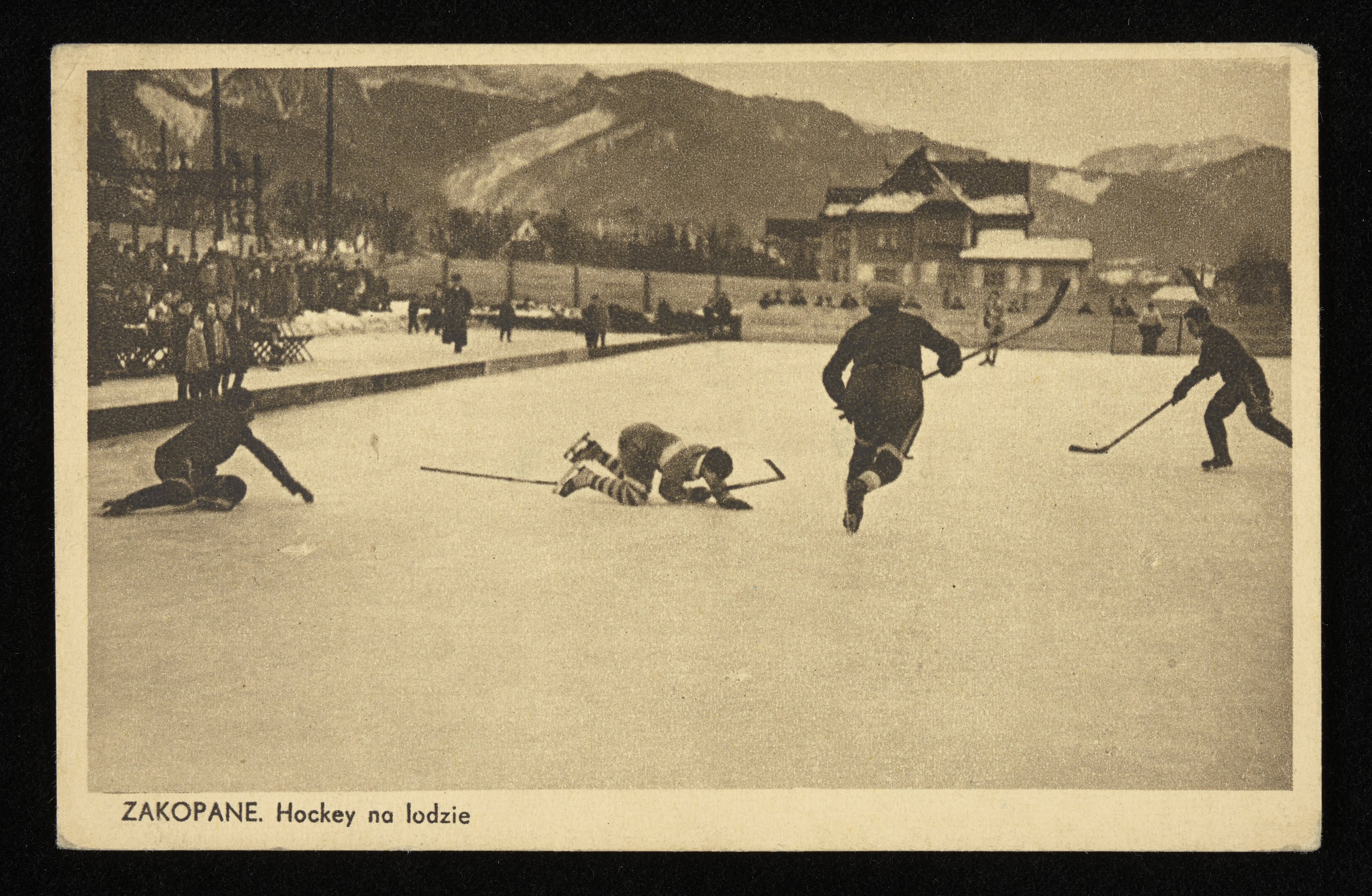 Schwarzes und weißes Foto von Menschen, die Hockey auf einem Eisstadion spielen, mit Gebäuden, Bäumen, Pfählen und Bergen im Hintergrund und Text unten.