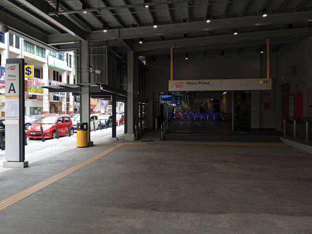 Leerer Parkhaus mit geparkten Autos, Betonpfeiler, Informationsschilder, Deckenbeleuchtung und Geb├Ąude mit Fenstern im Hintergrund.