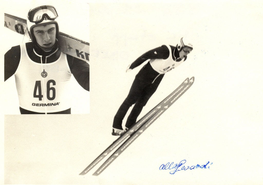 Schwarß-weißes Foto eines Skifahrers in der Luft, der einen Helm, eine Brille und Ski hält, mit Text unten.