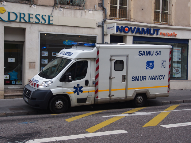 Ambulanz auf der Straßenseite vor einem Gebäude mit einem Krankenhausschild geparkt.