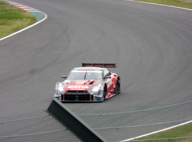 Ein Nissan GT-R Nismo GT3-Rennwagen auf der Nürburgring 24 Stunden-Strecke, umgeben von grünem Gras auf beiden Seiten.
