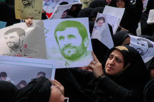 Eine Gruppe iranischer Frauen in schwarzer Kleidung, einige mit Brille, halten Fotos von Präsident Mahmoud Ahmadinejad während einer Kundgebung in Tehran hoch.