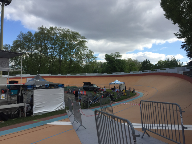 Gruppe von Radfahrern auf einer Schmutzpiste bei den UCI BMX-Weltmeisterschaften 2018, mit Zuschauern, Zelten und Fahrzeugen im Hintergrund.