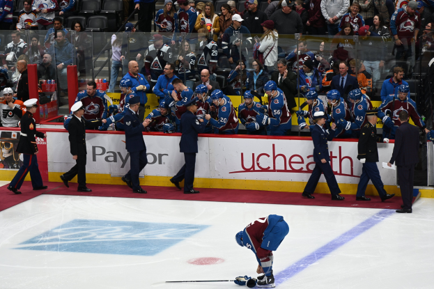Ein Hockey-Spieler in dunkler Uniform steht auf dem Eis umgeben von Zuschauern und Team-Mitarbeitern während eines Spiels der Colorado Avalanche gegen die San Jose Sharks am 24. März 2015.