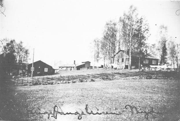 Ein Schwarz-Weiß-Foto eines Bauernhofs mit Häusern, Bäumen, Pfählen, Pflanzen und Gras im Vordergrund und einem Himmel im Hintergrund, mit Text unten, der lautet "Hans Christian Meyers Bauernhof in den frühen 1900er Jahren".