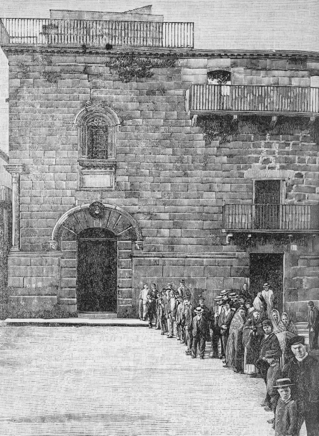 Schwarzes und weißes Foto einer Gruppe jüdischer Gefangener, die vor der Eingangstür einer Synagoge in Jerusalem stehen, mit einem Gebäude mit Fenstern, Geländern und einer Tür im Hintergrund.