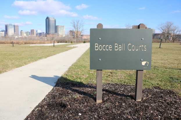 Ein Schild am Boden in der Nähe einer grasigen Fläche trägt die Aufschrift "Bocce Ball Courts in Indianapolis, Indiana".