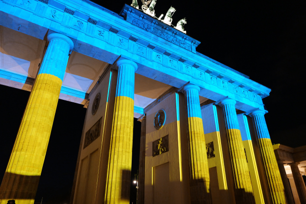 Das Brandenburger Tor in Berlin, Deutschland, erstrahlt in Blau und Gelb und präsentiert sich vor einem dunklen Hintergrund mit seinen Skulpturen.
