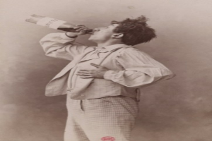 Ein Mann auf einem alten Schwarz-Weiß-Foto, mit ernster Miene, trinkt aus einer Flasche.